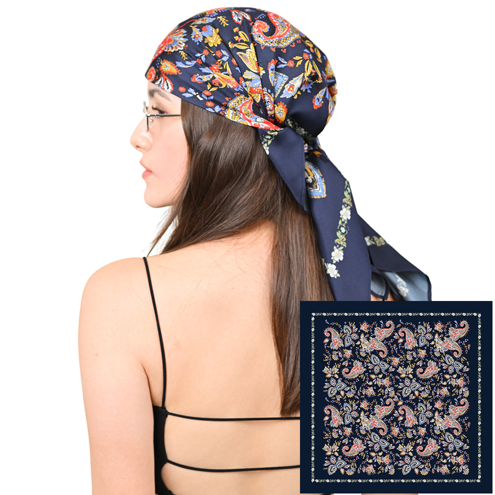 Model styling a navy silk scarf with red, pink, and gold paisley print as a headscarf